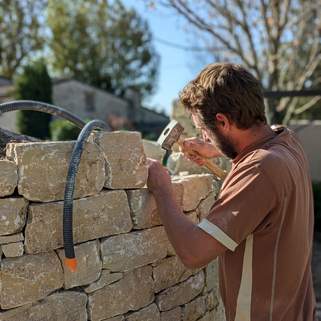 Photo de l'artisan qui travaille les pierres pour la nouvelle entrée